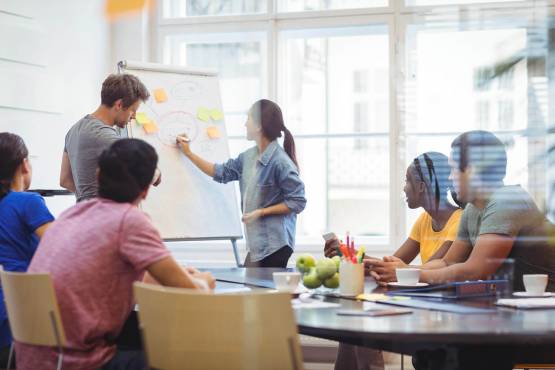 Woman using a whiteboard in a meeting with Colleagues