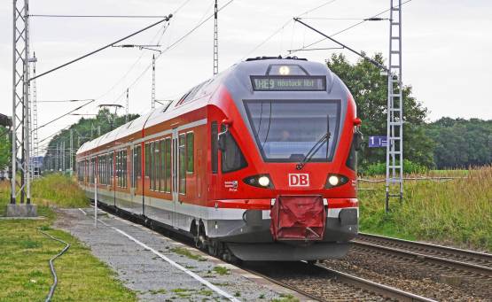 red-train-on-tracks-with-green-grass-beside-under-bright-sky